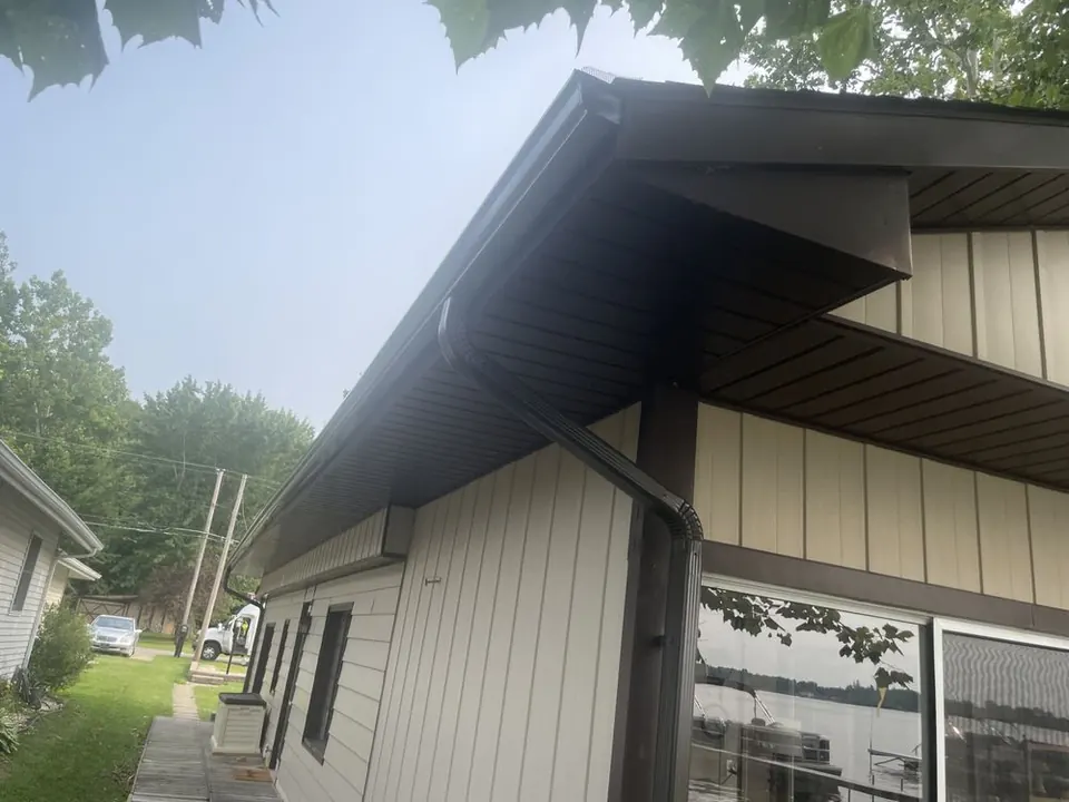 Dark gutter and downspout at the corner of a lakeside home